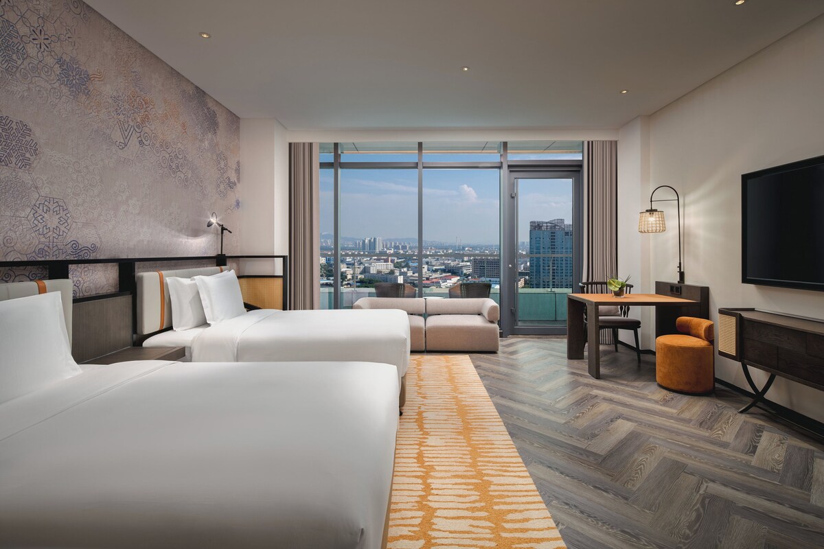 Une chambre d’hôtel avec deux lits, un canapé, un bureau et une télévision.