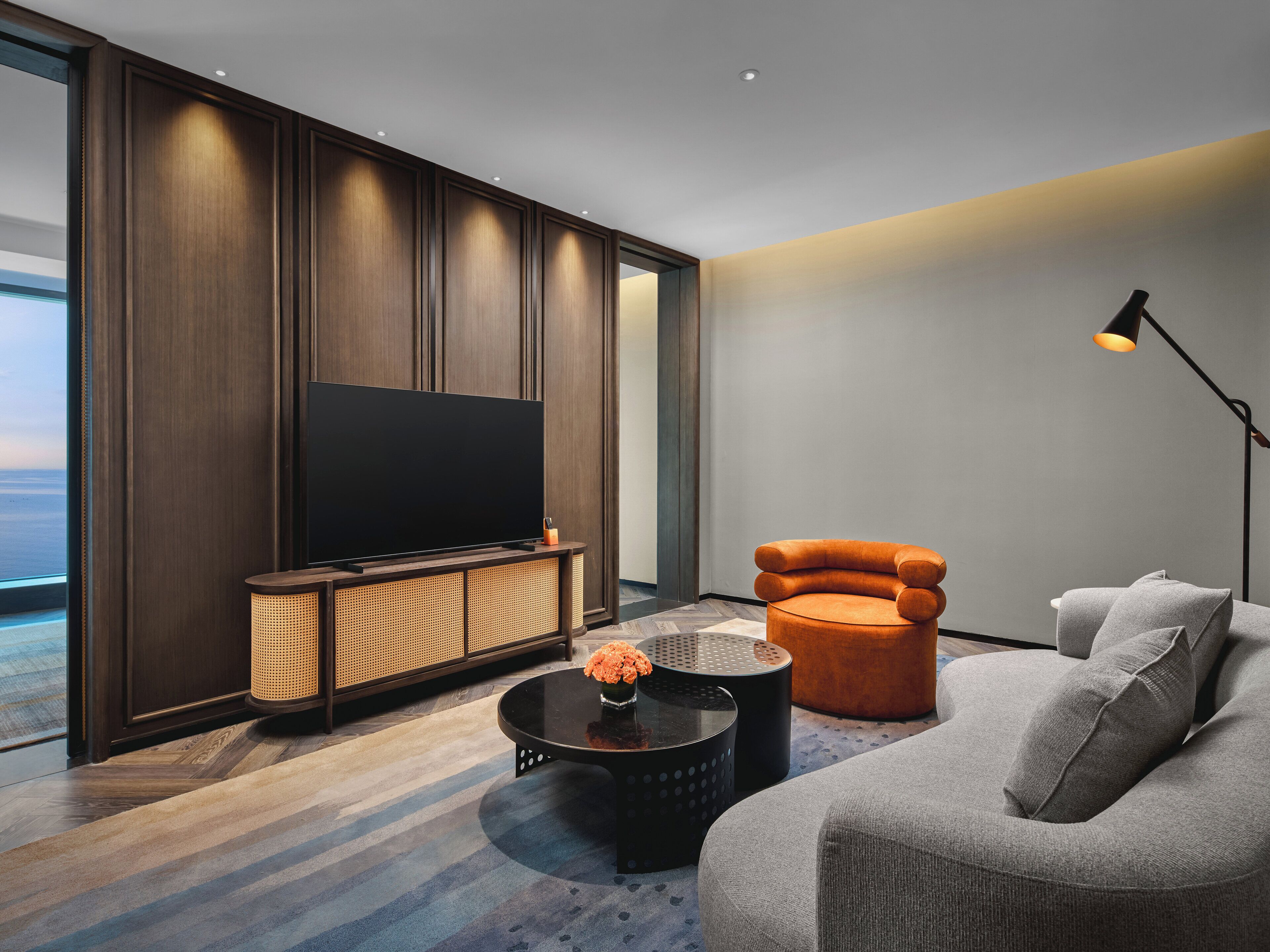Una sala de estar moderna con un televisor de pantalla plana grande, un sofá cómodo, un sillón elegante y una mesa de centro con un jarrón de flores.
