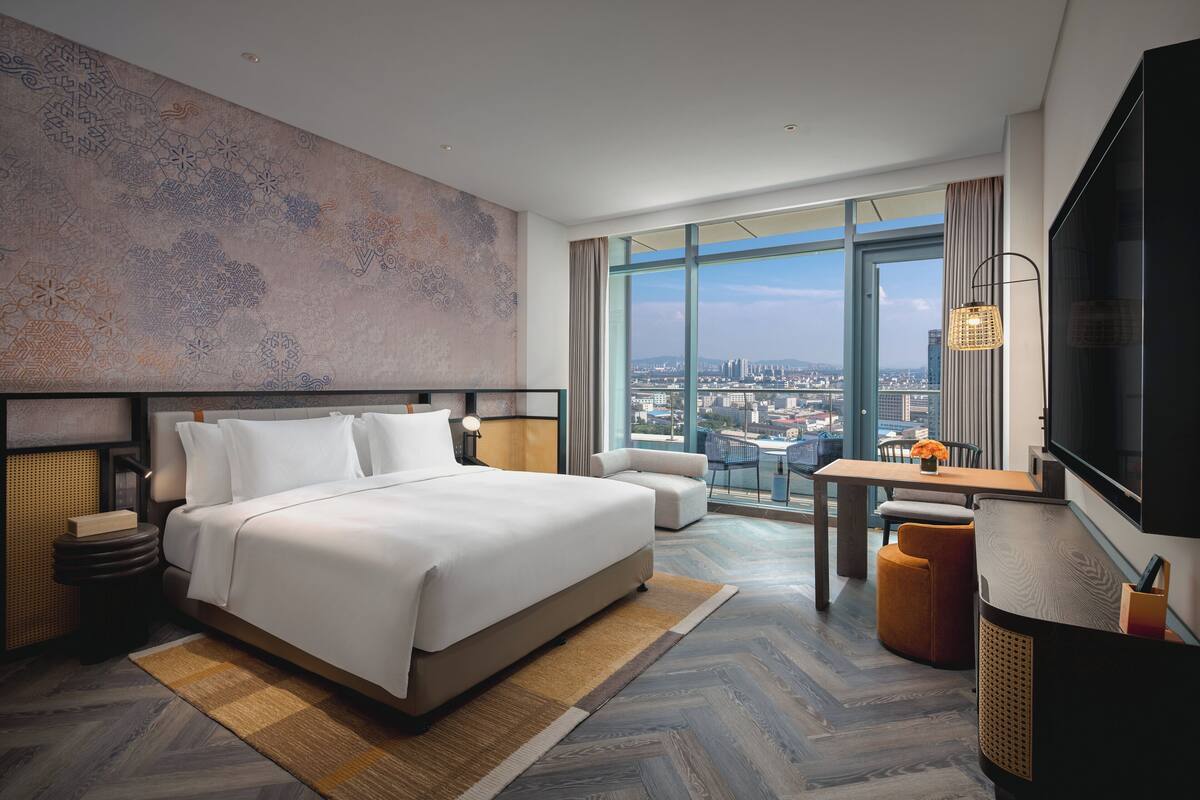 Een moderne hotelkamer met een groot bed, een bureau en uitzicht op de stad.