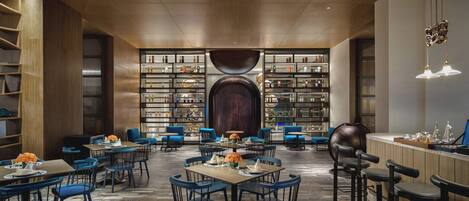 A spacious, modern interior with a central seating area, a bar, and a large bookshelf filled with various items.