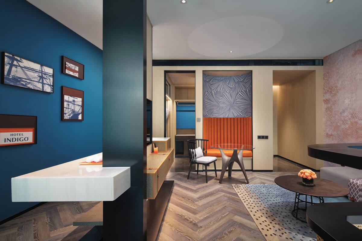 Een moderne hotel lobby met een receptiebalie, een zithoek en kunstwerken aan de muren.
