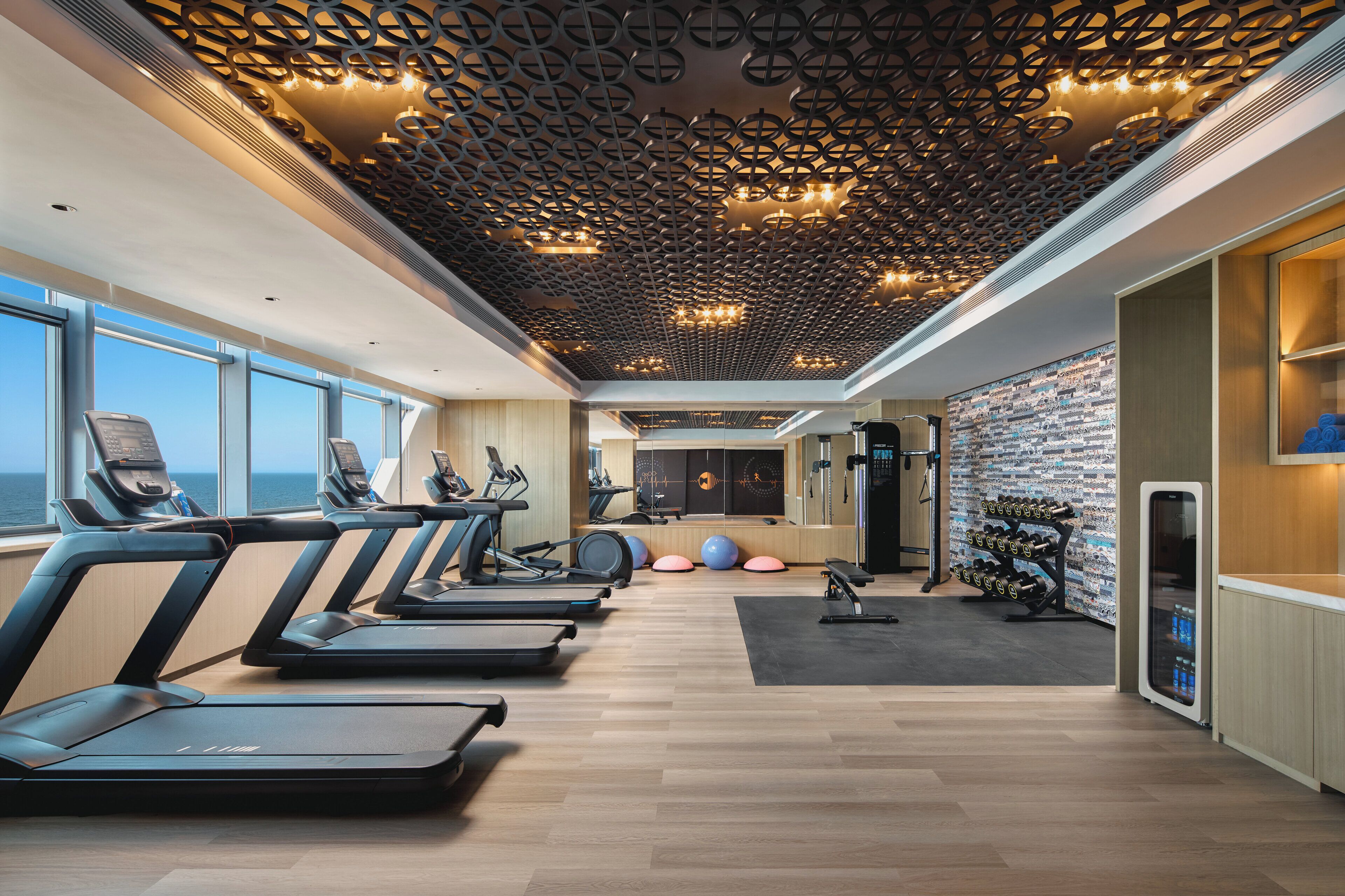 A gym with treadmills, exercise balls, and a wall of dumbbells.