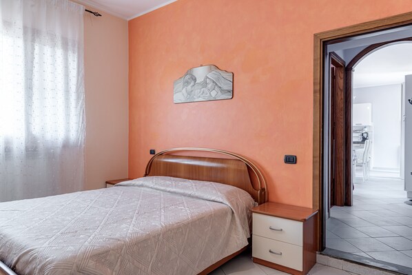 Une chambre à coucher avec un lit, une table de chevet et une œuvre d’art accrochée au mur.