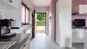 Une cuisine moderne équipée d’une machine à café, d’une télévision et offrant une vue sur le jardin.