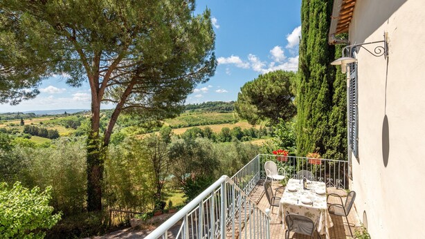 A balcony with a table set for dining, overlooking a scenic landscape with trees and hills. - Apartment 'Villa Caselunghe' with Shared Pool, Wi-Fi and Air Conditioning (Siena)
