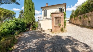 A gravel driveway leading to a building with a small brick entrance and a white facade. - Apartment 'Villa Caselunghe' with Shared Pool, Wi-Fi and Air Conditioning (Siena)