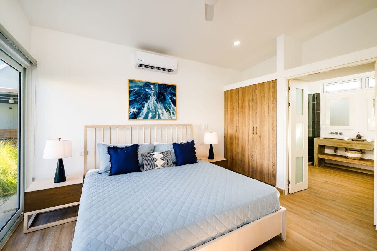 A modern bedroom with a large bed, wooden wardrobe, and a painting on the wall.