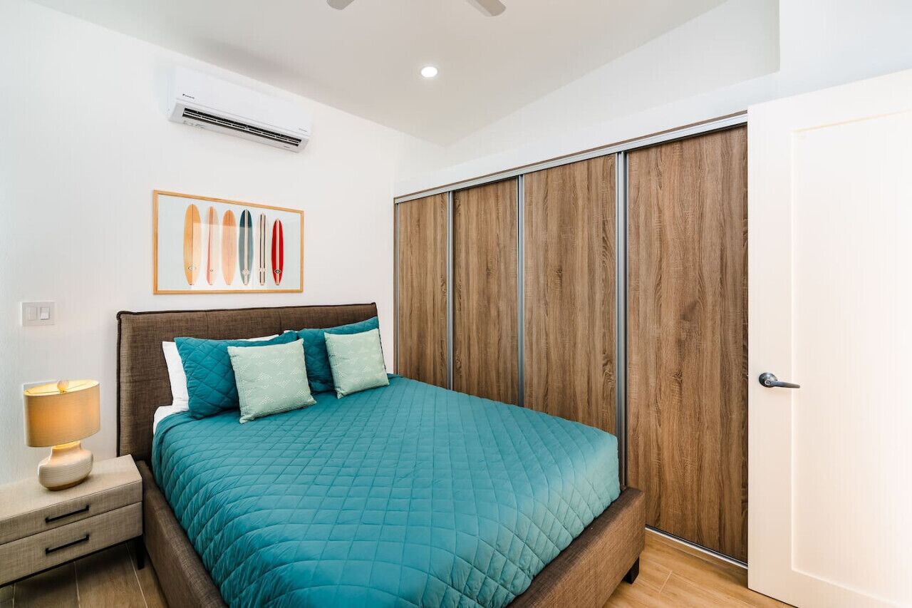 Een slaapkamer met een bed, nachtkastje en een houten garderobe.