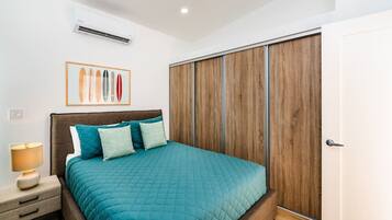 Een slaapkamer met een bed, nachtkastje en een houten garderobe.