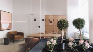 A modern lobby with a reception desk, seating area, and potted plants. - Aspasios Sofia Apartments (Madrid)