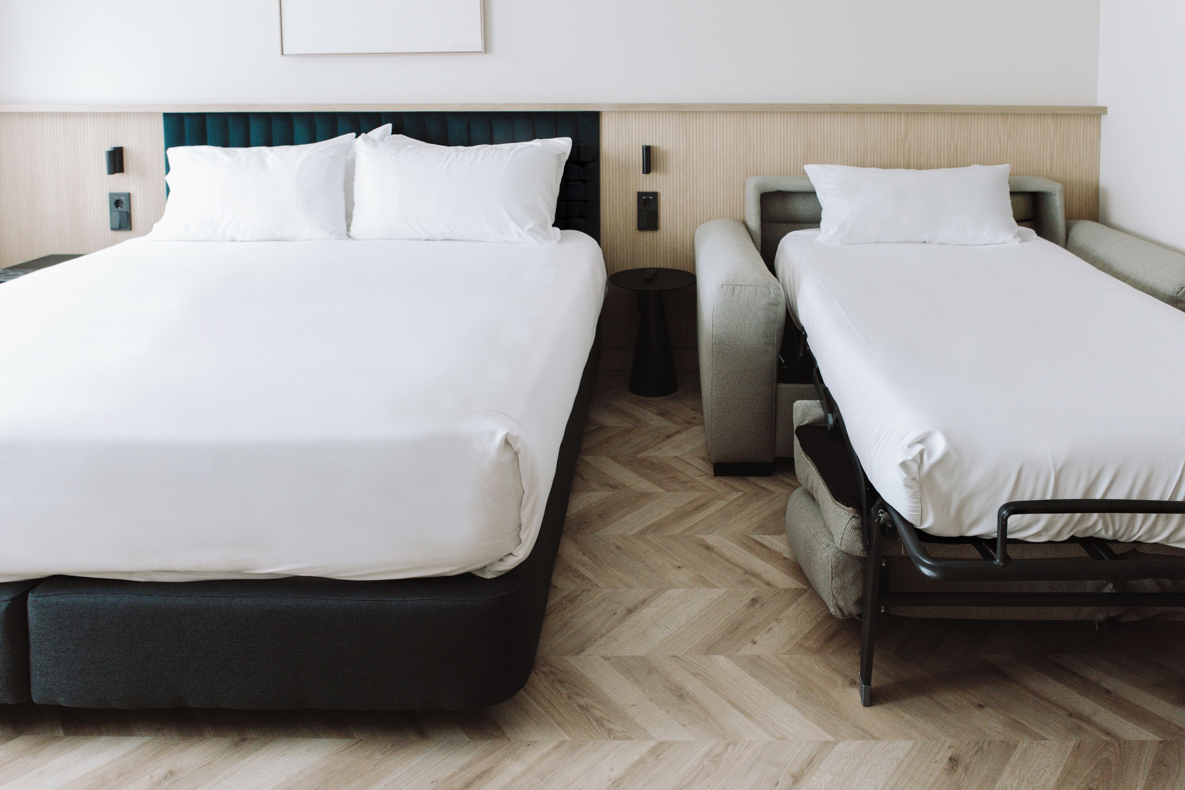 Habitación de hotel con dos camas, una mesita de noche, una silla y un teléfono instalado en la pared.