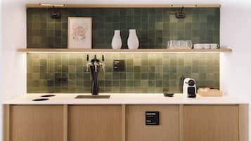 A kitchen with a white countertop, a coffee machine, and two white vases on a shelf above.