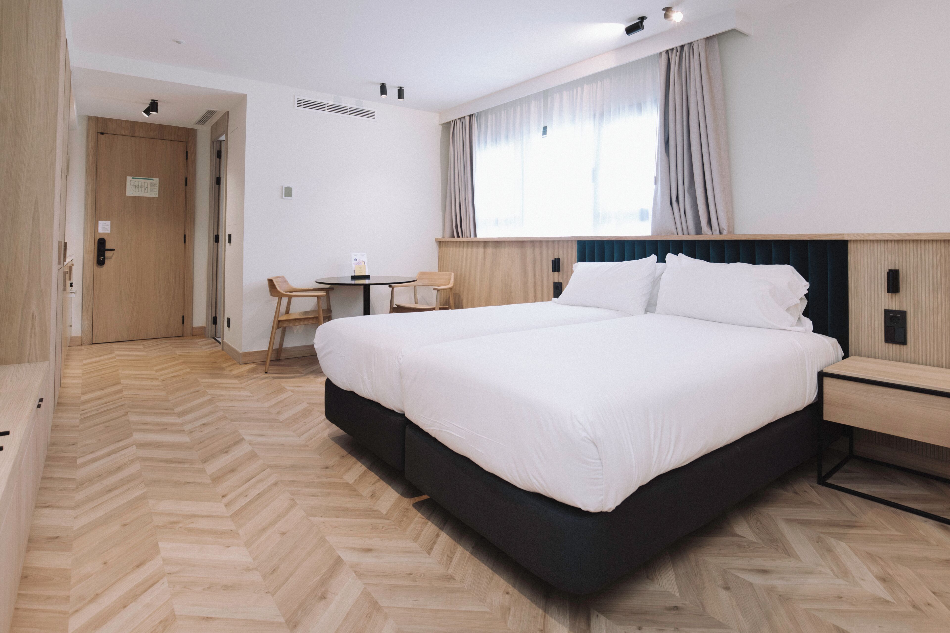A hotel room with a large bed, a desk, and a chair.