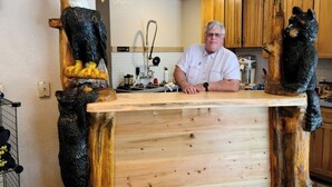 Una cocina con armarios de madera, una encimera de madera y una persona de pie detrás.