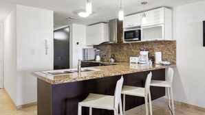 Eine moderne Küche mit Granit Arbeitsplatten, Edelstahlgeräten und weißen Barhocker.