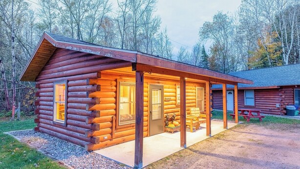 A log cabin with a covered porch and a visible kitchen area. - Perfect for Couples, Pet Friendly, Bear Theme, Log Cabin, Fireplace (Mountain)