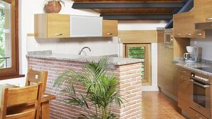 Una cucina con mobili in legno, un'isola in mattoni, illuminazione a sospensione e una macchina da caffè.