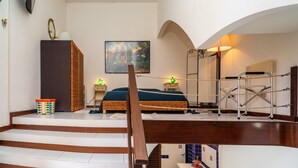 A bedroom with a bed, a dresser, a painting, and a staircase. - Apartment 'Casa Fabrizio' with Shared Terrace, Wi-Fi, and Air Conditioning (Taormina)