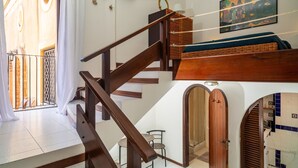 A staircase with a wooden handrail leading to a loft area with a bed and a wicker basket. - Apartment 'Casa Fabrizio' with Shared Terrace, Wi-Fi, and Air Conditioning (Taormina)