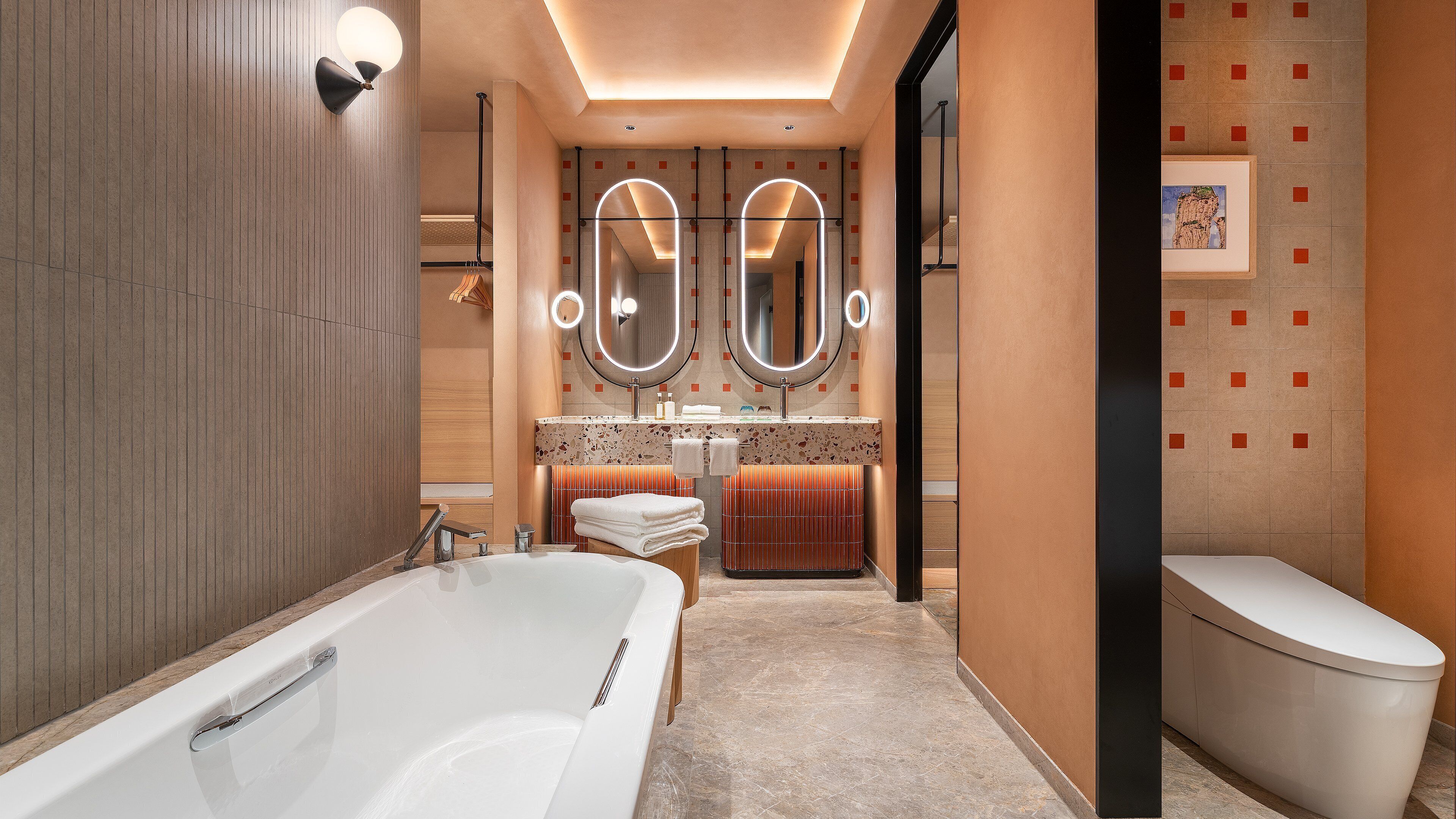 A modern bathroom with a large bathtub, two mirrors, a vanity with a sink, and a toilet.