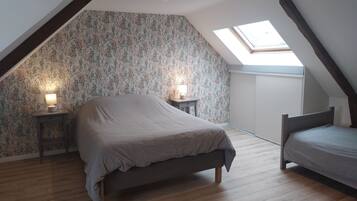 Ett sovrum med ett sluttande tak, en säng, ett sängbord med en lampa och ett takfönster.