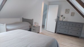 Un dormitorio con una cama grande, una mesita de noche, un aparador y una puerta que da a otra habitación.