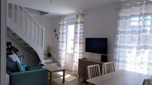 Una sala de estar moderna con una escalera, un televisor y una zona de comedor.