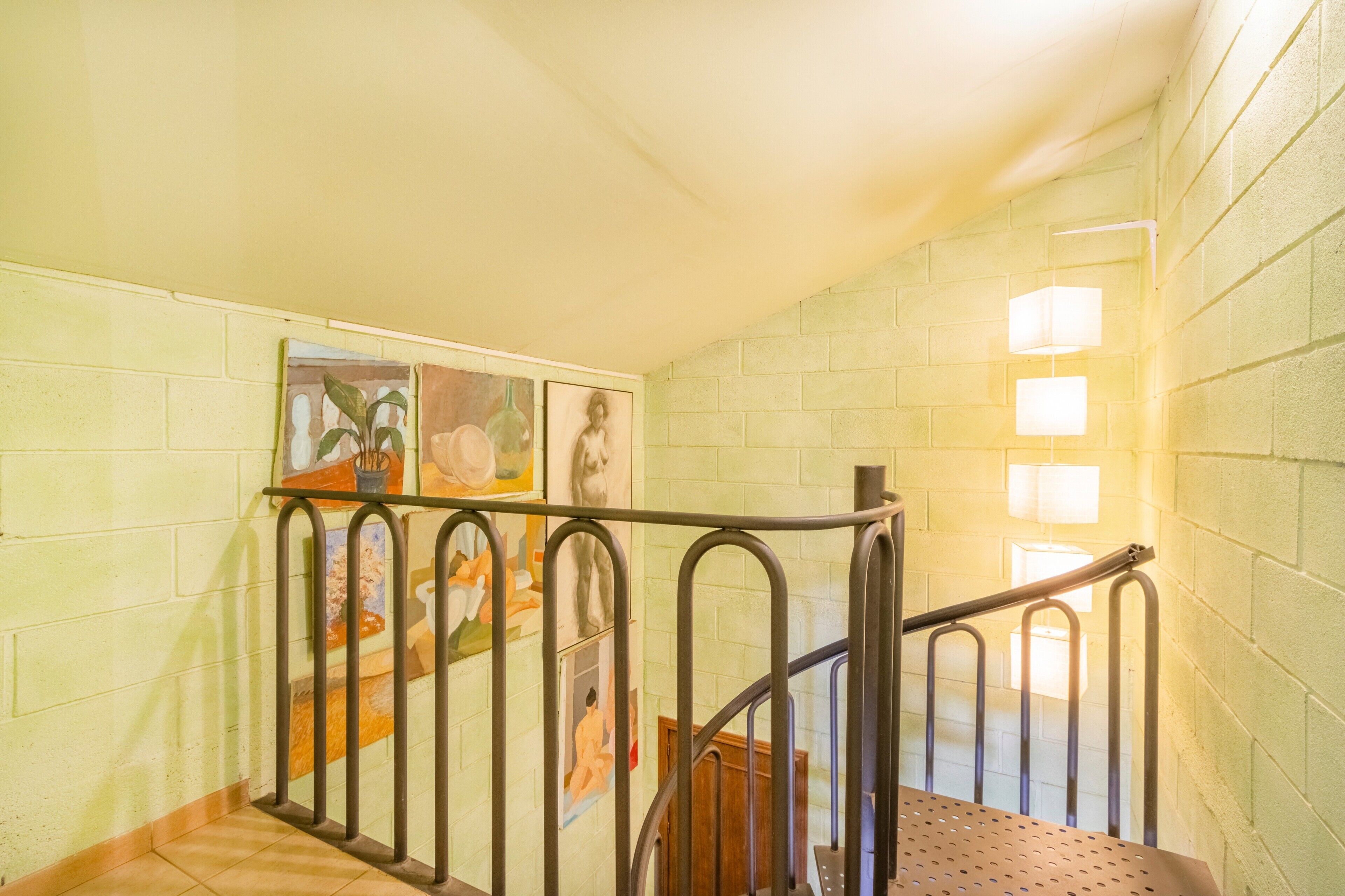 A staircase with metal railings, a tiled floor, and a wall with artwork.