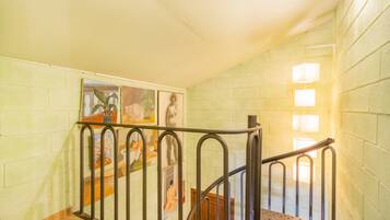 A staircase with metal railings, a tiled floor, and a wall with artwork.