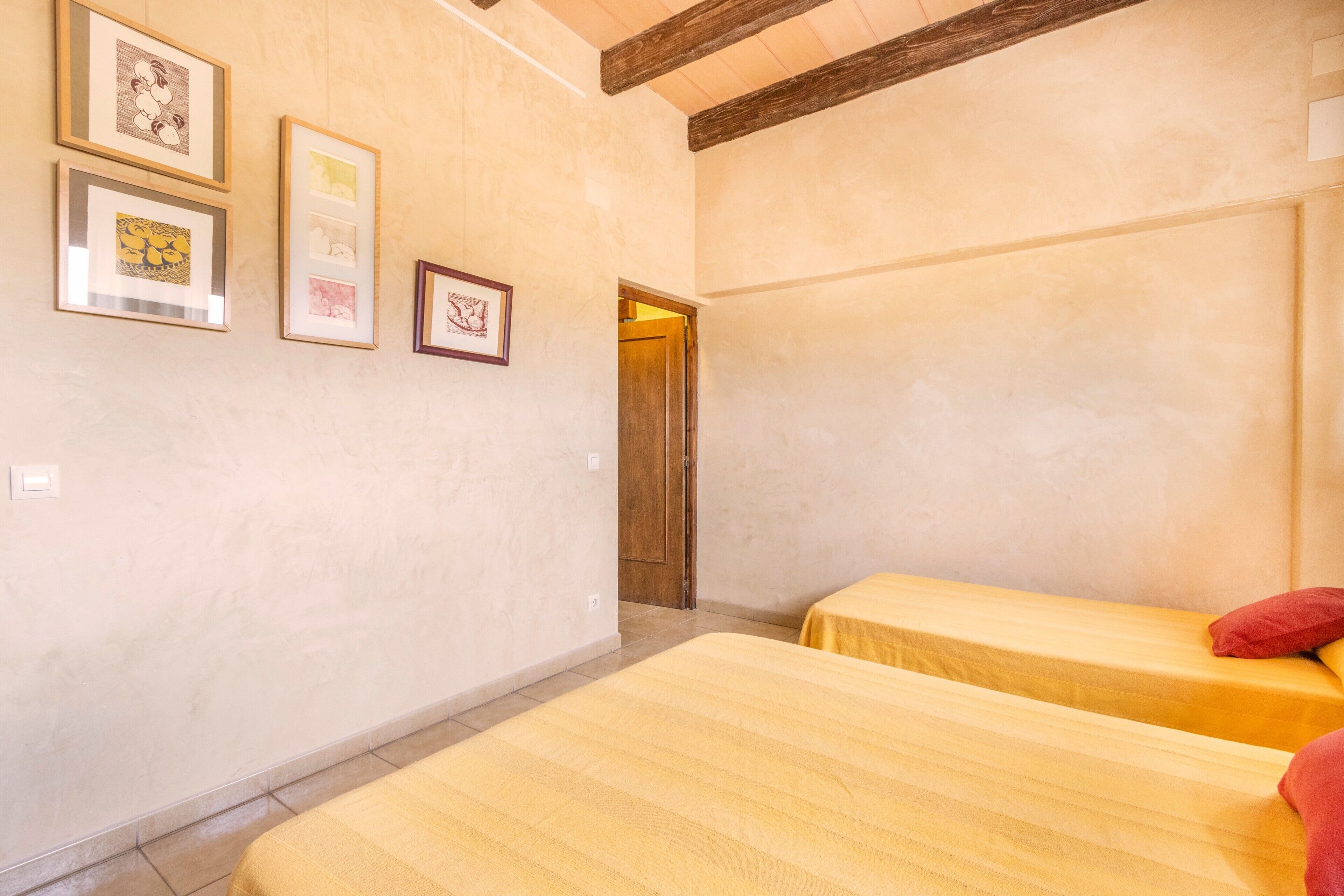 A room with two beds, a wooden door, and framed pictures on the wall.