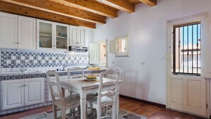A kitchen with white cabinets, a tiled backsplash, and a wooden ceiling. - Casa Amalfitana by Wonderful Italy (Syracuse)