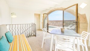 Ein Balkon mit Tisch, Stühlen, einer Couch und Blick aufs Meer.