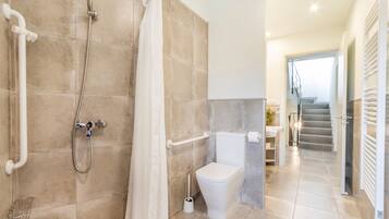 A bathroom with a shower, toilet, and a handrail.