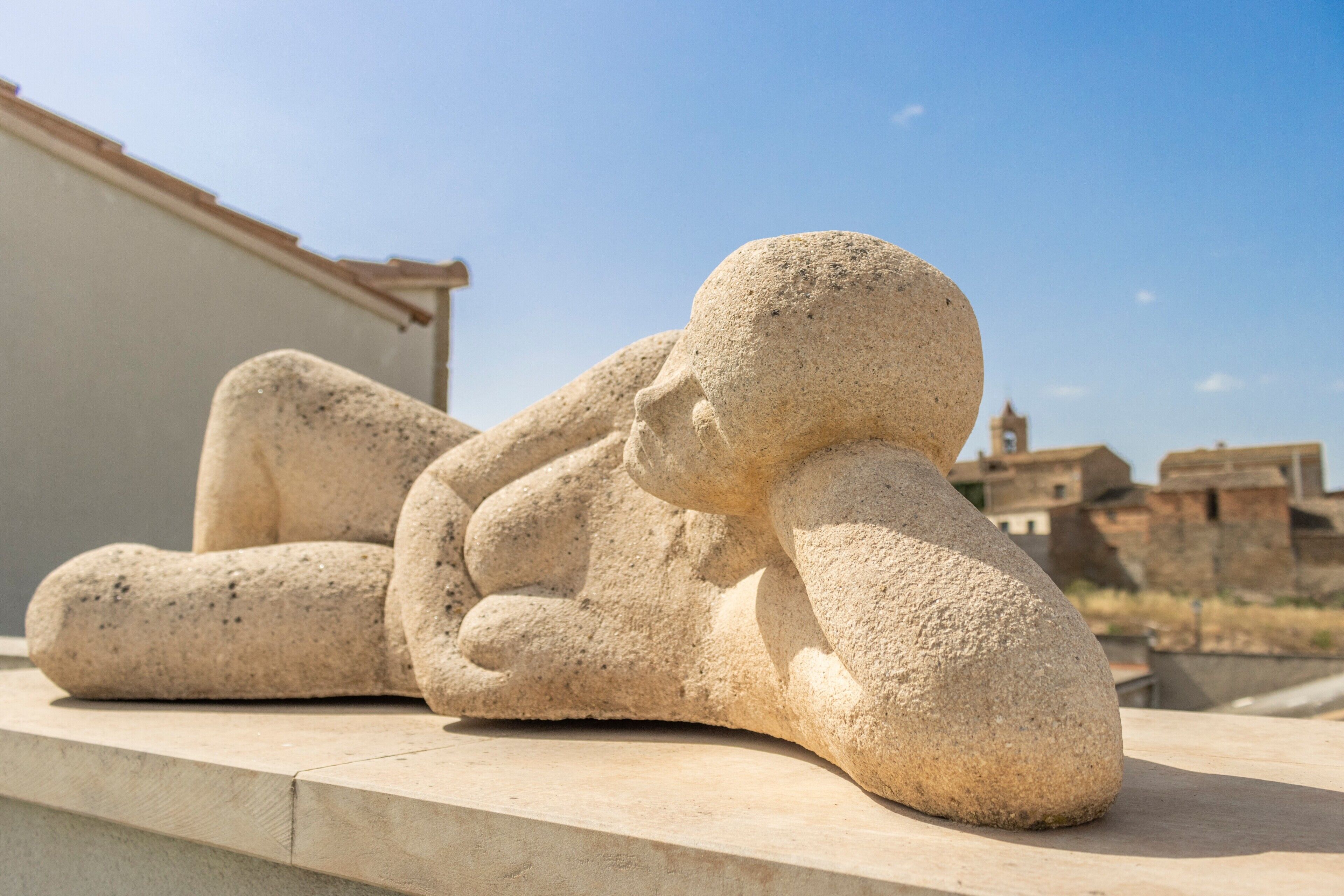 A stone sculpture of a reclining figure on a ledge.