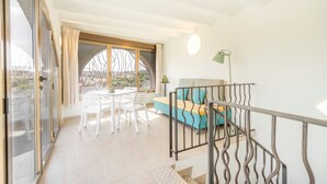 Ein Balkon mit Esstisch und Stühlen, einer Couch mit Kissen sowie eine Treppe mit Geländer.