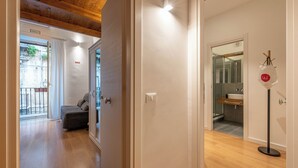 A hallway with a wooden ceiling, a grey sofa, and a bathroom with a sink and mirror. - Casa Abbanniata a Ballaro' by Wonderful Italy (Palermo)