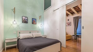 A bedroom with a bed, bedside tables, a nightstand, a wall-mounted light fixture, and a picture frame. - Casa Abbanniata a Ballaro' by Wonderful Italy (Palermo)
