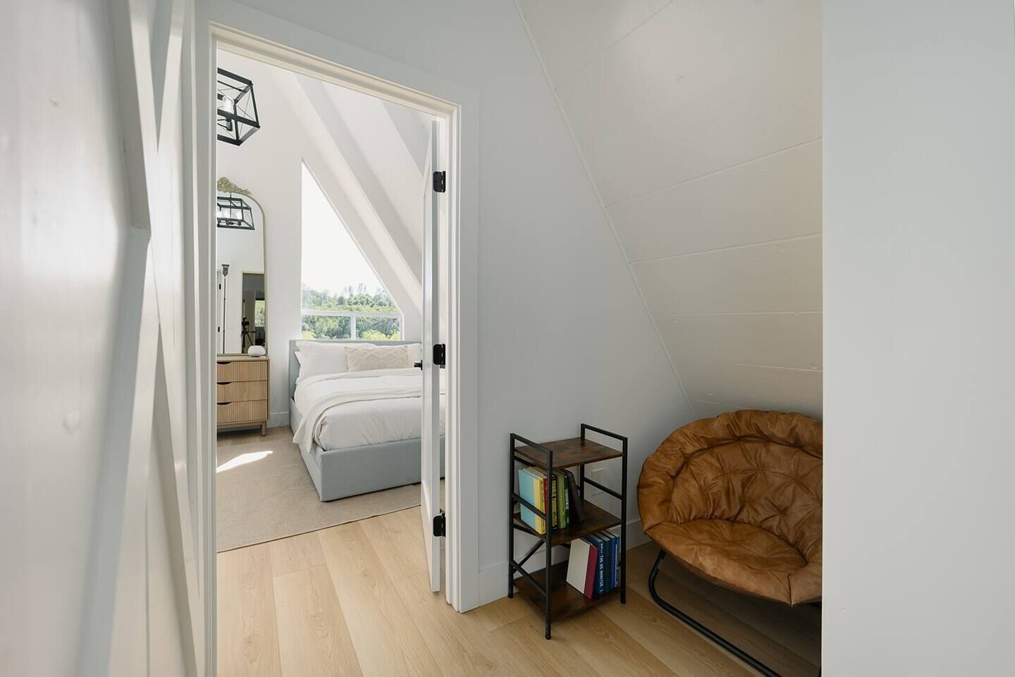 Ein Schlafzimmer mit einem Bett, einem Bücherregal und einem braunen Sessel.