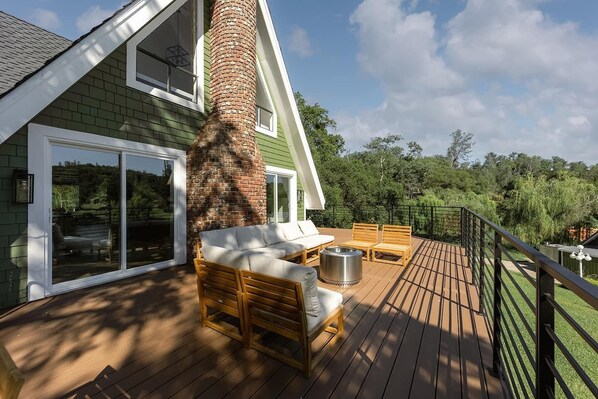 A deck with outdoor furniture, a brick chimney, and a view of the surrounding greenery. - -Sleeps 14<br>-Lakefront<br>-Private Pool<br>-Jacuzzi<br>-Sauna<br>-Near Golf Course (Auburn)