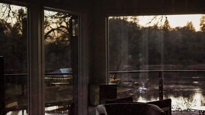 A room with large windows overlooking a body of water, a fireplace, and a seating area with a table and chairs. - Treehouse Overlook at Lakewood (Auburn)