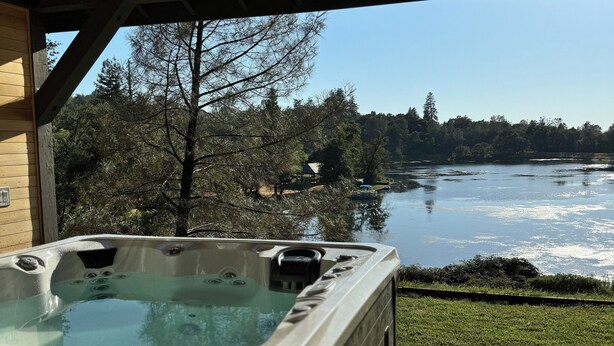 A hot tub with a view of a lake and forest. - Treehouse Overlook at Lakewood (Auburn)