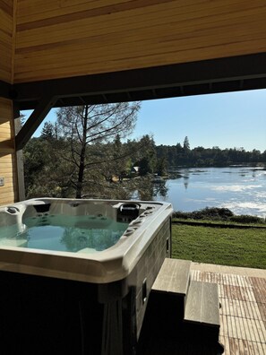 A hot tub with a view of a lake and forest. - Treehouse Overlook at Lakewood (Auburn)
