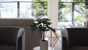 A room with two armchairs, a coffee table with a tray, a potted plant, and a view of a lake through large windows. - Treehouse Overlook at Lakewood (Auburn)