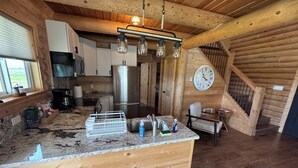 A rustic kitchen with wooden walls, a large clock, and a wooden staircase. - Private Teton Basin Adventure Cabin! Hike, Ski, Fish, Close to Jackson (Tetonia)