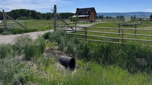 A rural landscape with a wooden house, a gravel path, and a fenced area. - Private Teton Basin Adventure Cabin! Hike, Ski, Fish, Close to Jackson (Tetonia)