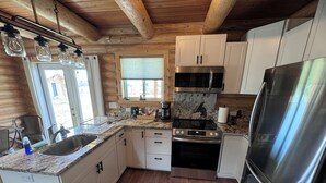A modern kitchen with wooden beams, stainless steel appliances, and a granite countertop. - Private Teton Basin Adventure Cabin! Hike, Ski, Fish, Close to Jackson (Tetonia)