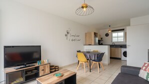 Ein modernes Wohnzimmer mit Flachbildfernseher, einer Holzunterhaltungsecke und einem Essbereich mit Tisch und Stühlen.