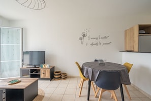 Ein zeitgemäßer Wohnraum mit Essbereich, Fernseher und einer Wand mit einer dekorativen Schrift.