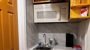 Una cuina compacta amb microones integrat, rentaplatets i un bany.