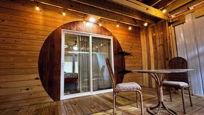 Un interior de fusta amb una porta de vidre que dona a una habitació, una cadira de vimet i una taula rodona petita.